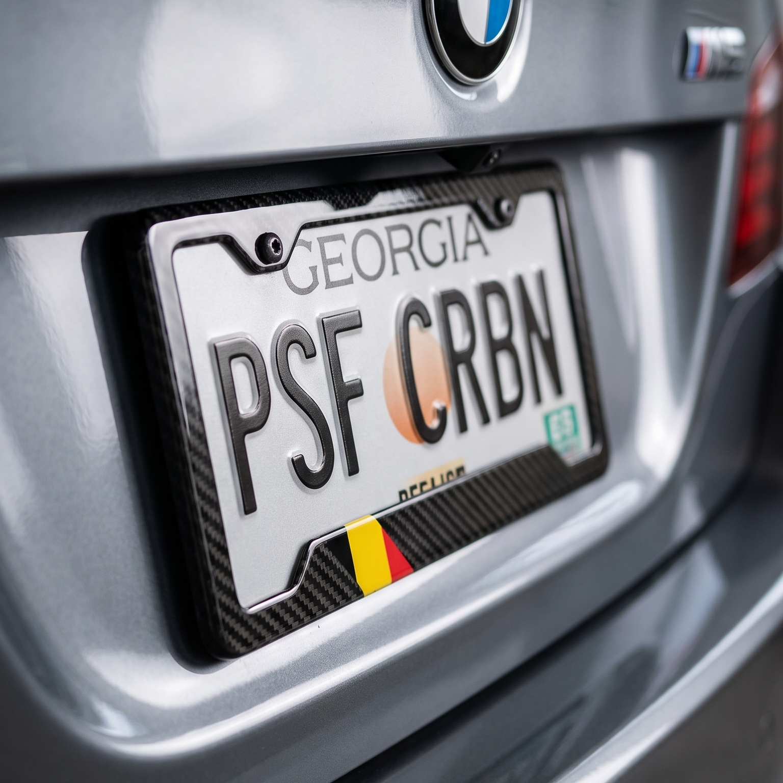 Belgium flag carbon fiber license plate frame close-up on gray BMW M5