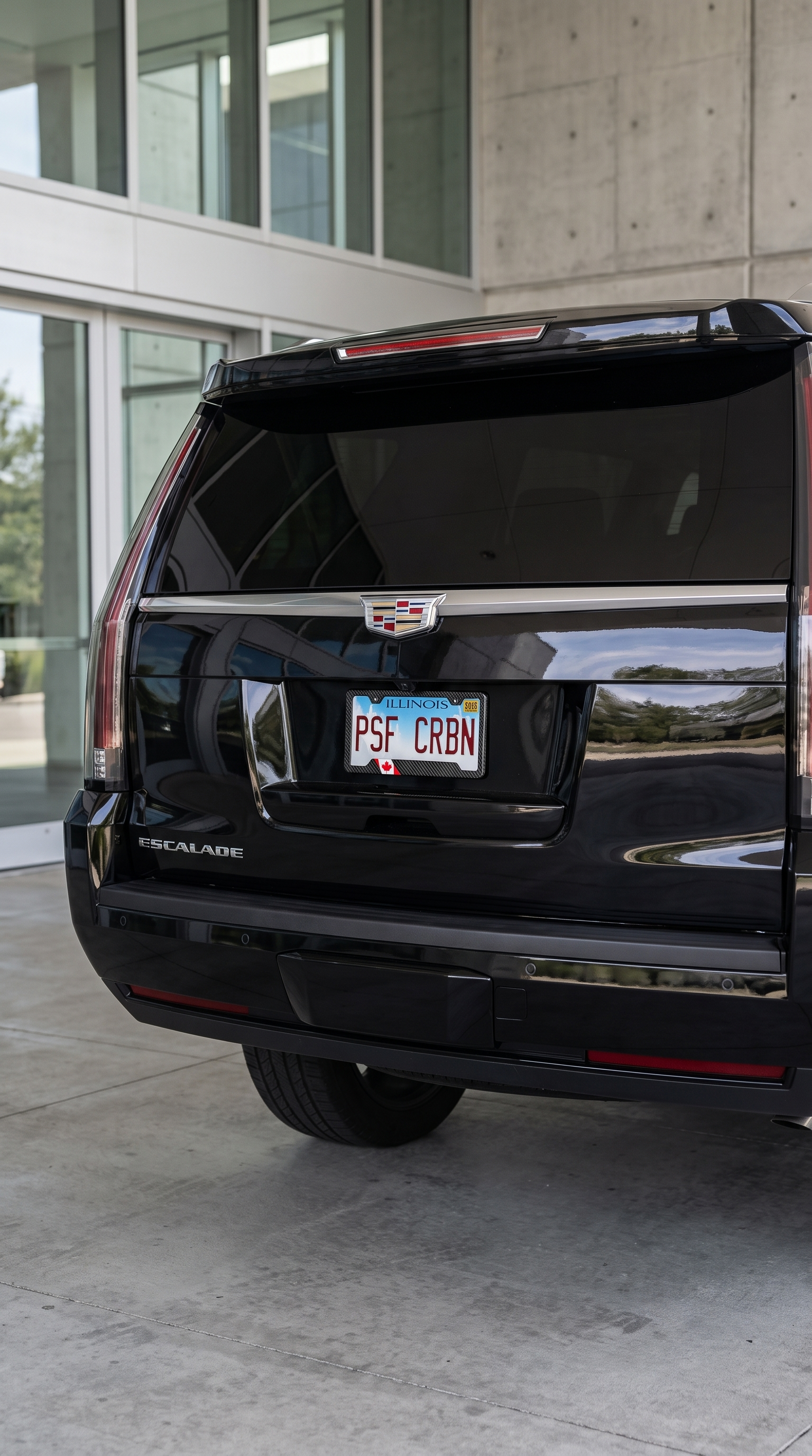 Canada flag carbon fiber license plate frame on gloss black Cadillac Escalade, wide rear view