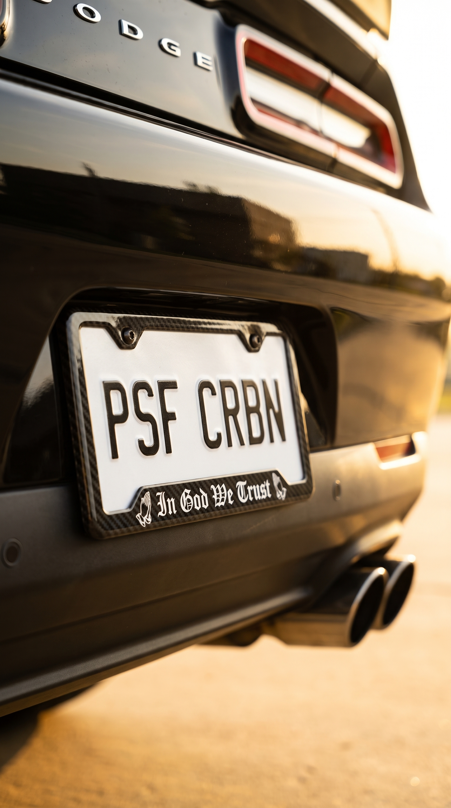 In God We Trust praying hands carbon fiber plate frame on a black Dodge Challenger