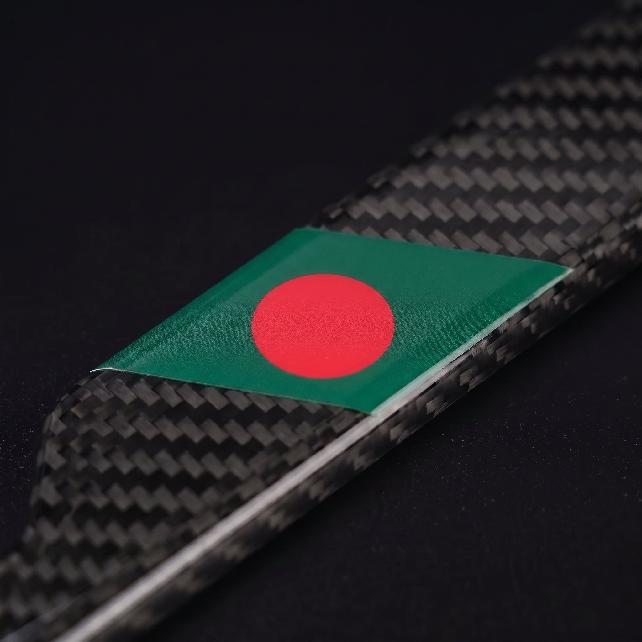 Macro of the Bangladesh flag inlay on a PSF Carbon carbon fiber license plate frame