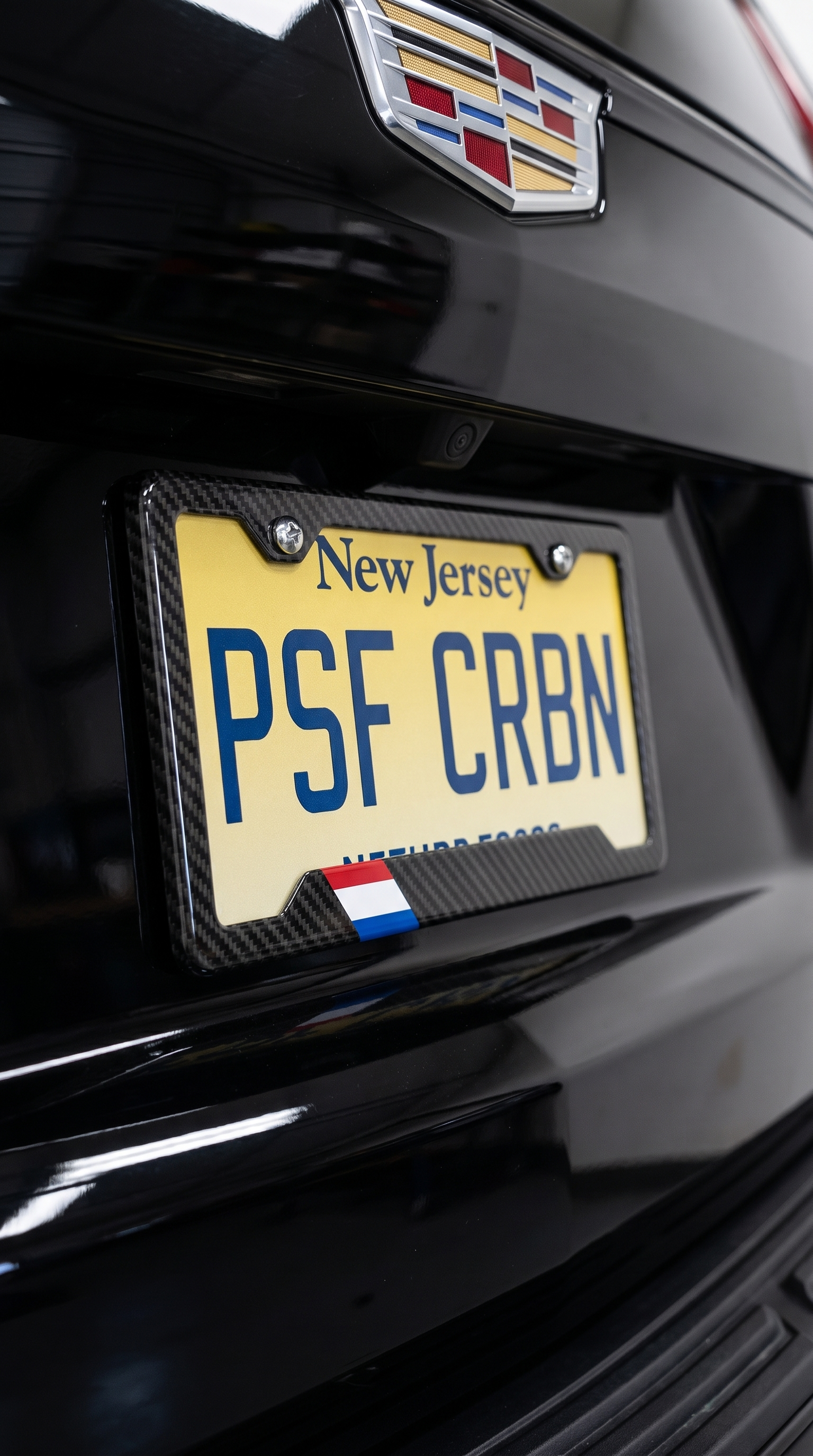 Netherlands flag carbon fiber license plate frame close-up on black Cadillac Escalade