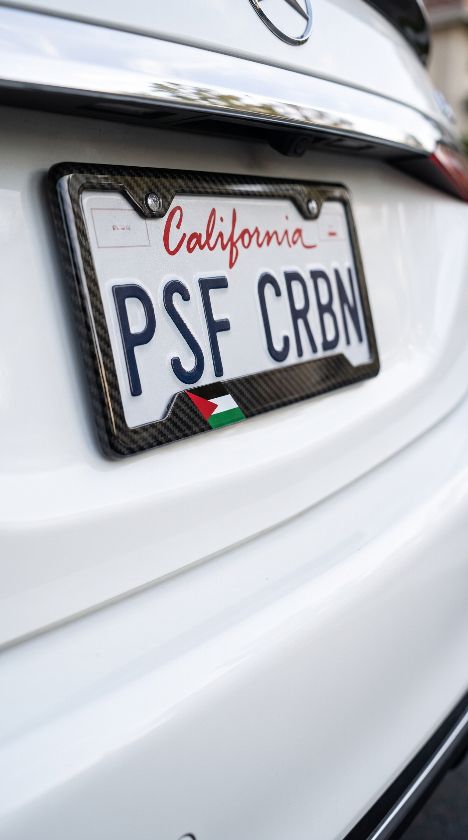 Palestine flag carbon fiber plate frame close-up on white Mercedes S-Class, California plate PSF CRBN