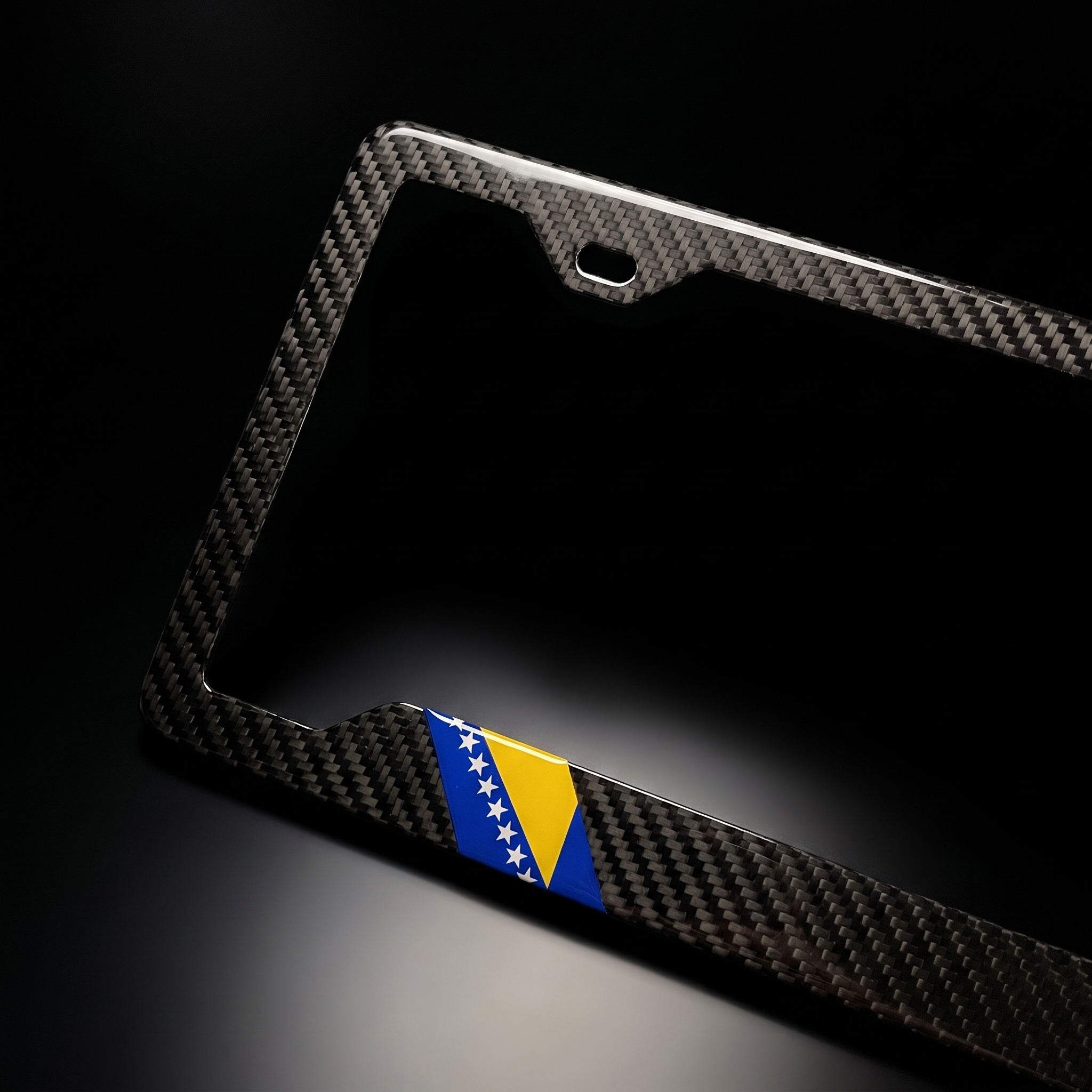 Bosnia and Herzegovina flag carbon fiber license plate frame — angled macro detail of carbon weave and flag chip