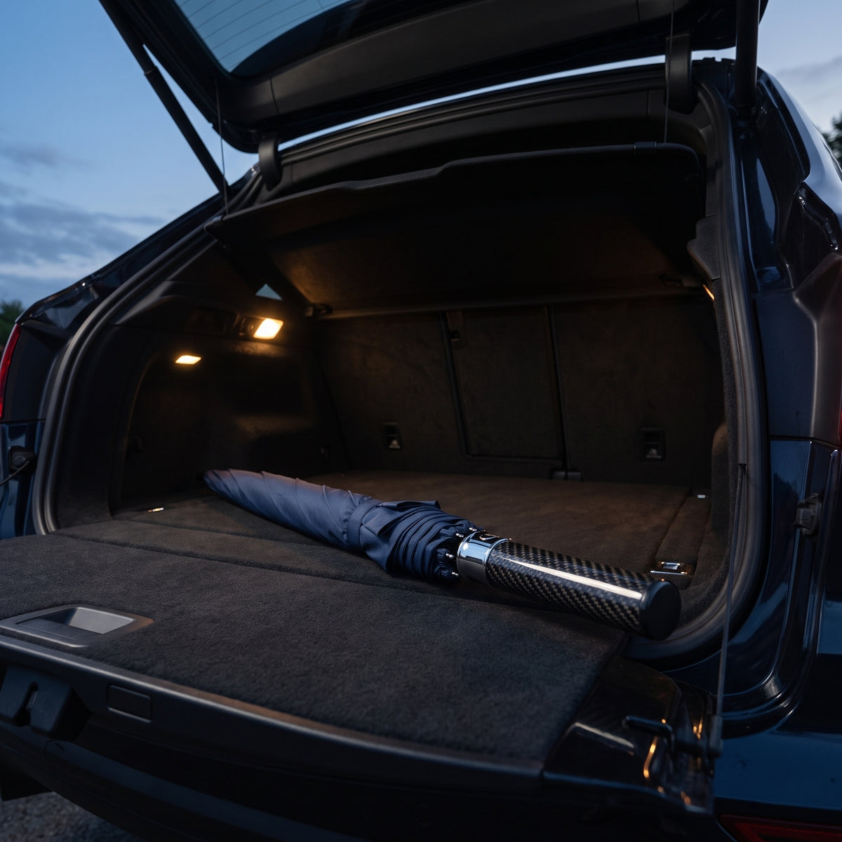 PSF Carbon Fiber Umbrella closed and tied, lying in the open trunk of an SUV